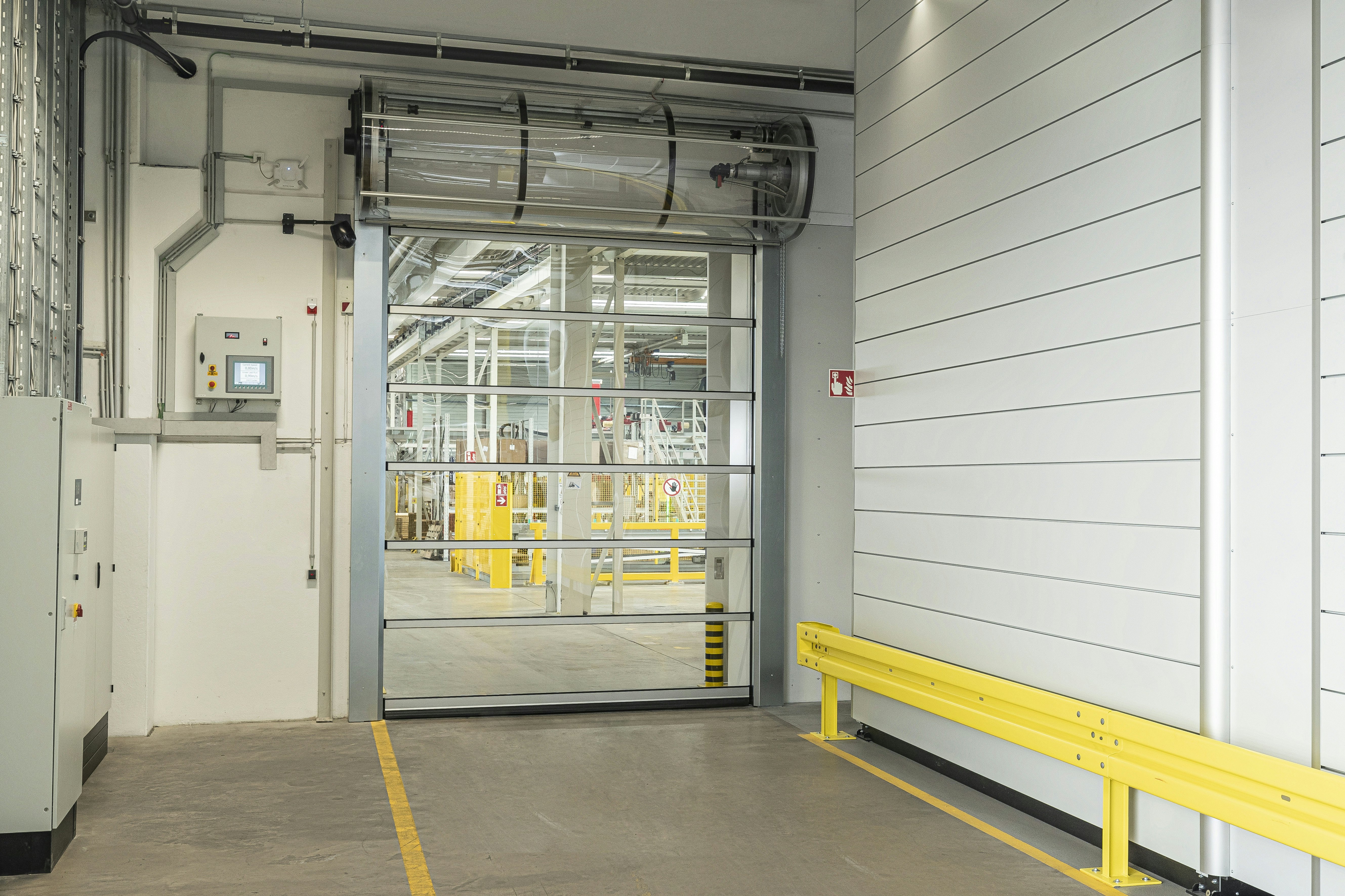 With its impact-resistant and transparent polycarbonate sections, the world’s fastest vertically opening industrial high-speed door can easily withstand the demands of tough everyday industrial use. Industrial hall with fitted transparent spiral door.