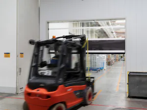 Good reasons to choose Hörmann high-speed doors and... Black red forklift drives towards an opening, semi-transparent high-speed door