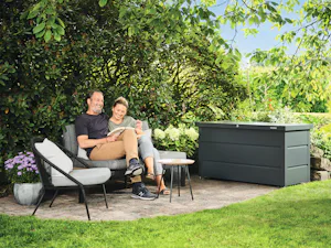 Zuhause ist der Ort für die wertvollsten Erinnerungen und... Mann und Frau sitzen neben Gartenbox auf Bank im Garten