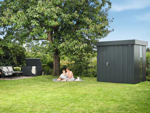 Zuhause ist der Ort für die wertvollsten Erinnerungen und... Mutter und Kind sitzen vor Gerätehaus im Garten auf einer Decke