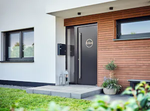 Een goede indruk begint met een Antraciet kleurige moderne voordeur in huis met houten accenten | Hörmann