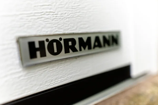 Foto van het embleem van Hörmann op een witte garagedeur in Almelo.