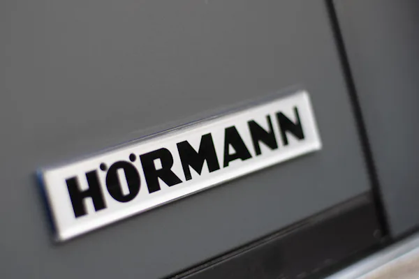 Detailfoto van een Hörmann logo op de hoek van een NT60-2 openslaande garagedeur