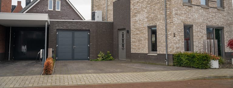 Lichtgekleurd huis met donkere garage. In de garage zit een antracietkleurige openslaande garagedeur van Hörmann.
