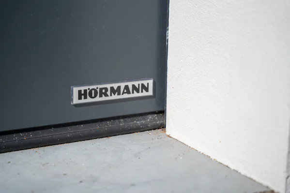 Detailfoto van een Hörmann sectionaaldeur, op de foto is het logo van Hörmann te zien in de rechter onderkant van de sectionale garagedeur