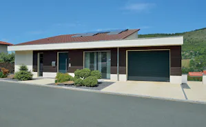 Kenmerken die roldeuren praktisch en Moderne bungalow met zwarte Hörmann roldeur, houten gevelaccenten en zonnepanelen op het dak.