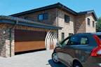 Maak het gebruik van uw garagedeur nog gemakkelijker met de... Donker grijze auto geparkeerd voor klassieke woning met een Hörmann garage.