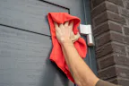 Vind een dealer in uw buurt Nt80-2 Openslaande garagedeur wordt schoongemaakt met een rood doekje en de schoonmaakset van Hörmann