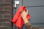 Vind een dealer in uw buurt Nt80-2 Openslaande garagedeur wordt schoongemaakt met een rood doekje en de schoonmaakset van Hörmann