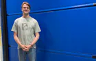 Marijn, medewerker Marketing, voor een blauwe Hörmann deur.