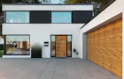 Hörmann ThermoCarbon voordeur met houtlook, glaspanelen aan weerszijden en bijpassende garagedeur in moderne gevel.