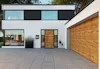 Hörmann ThermoCarbon voordeur met houtlook, glaspanelen aan weerszijden en bijpassende garagedeur in moderne gevel.