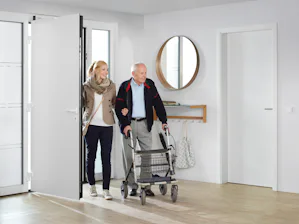 Nie mehr Schlüssel suchen – öffnen Sie Ihre Haustür ganz... Automatischer Türantrieb von Hörmann öffnet Haustür für älteres Paar mit Rollator