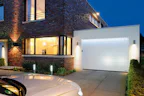 Maak het gebruik van uw garagedeur nog gemakkelijker met de... Zilveren auto geparkeerd voor moderne woning met een Hörmann garage.