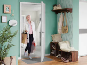Oft sind es die kleinen Dinge, die den Alltag erleichtern... Frau mit Einkaufstüten öffnet Wohnungstür mittels Handsender