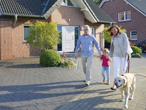 Sicherheit, Geborgenheit und ein herzliches Willkommen: Die... Glückliche Familie mit Hund vor Einfamilienhaus mit weißer Haustür
