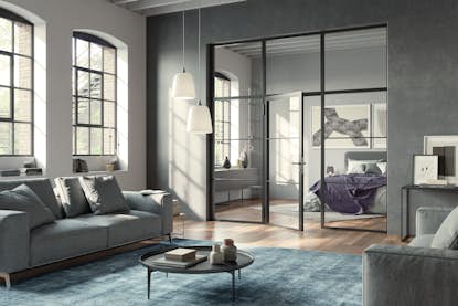 Das Bild zeigt eine modern eingerichtete Loft-Wohnung mit hohen Decken und einer Stahl-Glas-Trennwand mit Glastür. Genannt wird der Wohn- und Einrichtungsstil dieses Apartments „Industrial Style“. Das Bild zeigt eine modern eingerichtete Loft-Wohnung mit hohen Decken und einer Stahl-Glas-Trennwand mit Glastür. Genannt wird der Wohn- und Einrichtungsstil dieses Apartments „Industrial Style“.