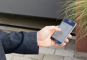 Veiligheid en comfort Persoon gebruikt via zijn telefoon het Bisecur systeem van Hörmann.
