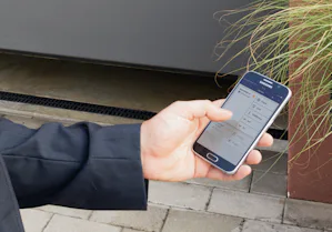 Veiligheid en comfort Persoon gebruikt via zijn telefoon het Bisecur systeem van Hörmann.