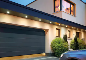 Elektrische garagedeur | Sectionaaldeur Hörmann Een auto wacht tot de elektrische garagedeur opengaat. Deze garagedeur is een sectionaaldeur van Hörmann.