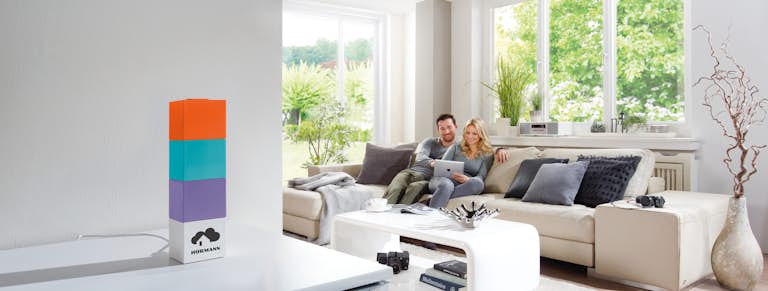 Mann und Frau sitzen auf dem Sofa und bedienen ein Tablet.