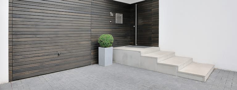 Antracietkleurige met hout aangekleedde kanteldeur van Hörmann. De garagedeur is geplaatst in een wit modern uitziend huis.