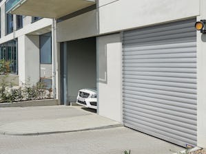 Garagedeuren voor collectieve garages -  Auto rijdt door open roldeur