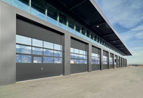 Portes sectionnelles industrielles Sectionaaldeuren, ook wel overheaddeuren genoemd, gaan verticaal open en daarmee ontstaat ruimte vóór en achter de deur