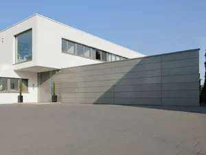 Portoni in alluminio per una pannellatura a cura del cliente Per una configurazione del portone e della facciata particolarmente personalizzata, vengono utilizzati portoni con la possibilità di una pannellatura in loco, ad es. in edifici esclusivi e garage...