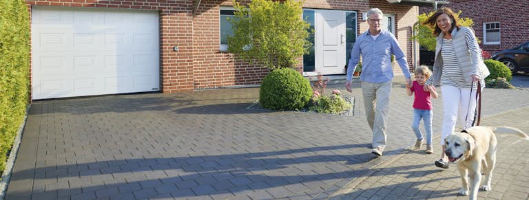 Familie mit Hund vor einem Haus mit sicherer Haustür und einem Garagentor