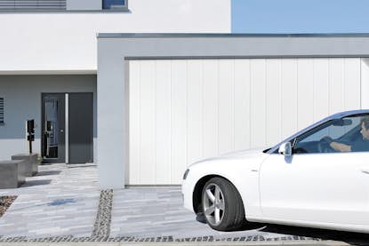 Parkendes Auto vor weissem Seitensectionaltor von Hörmann Parkendes Auto vor weissem Seitensectionaltor von Hörmann