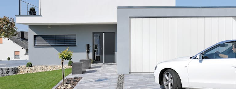 Parkendes Auto vor weissem Seitensectionaltor von Hörmann
