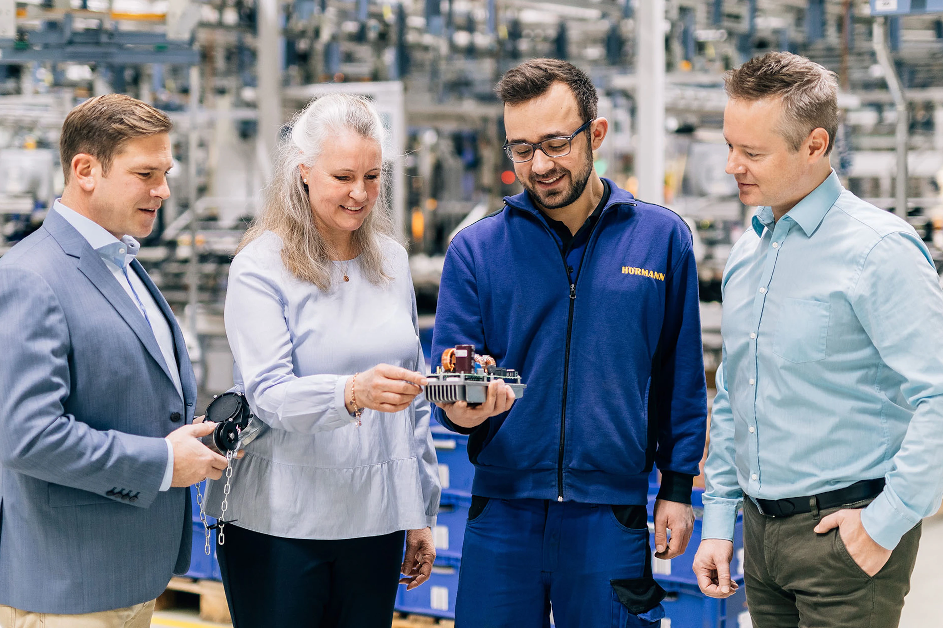 Vier medewerkers van Hörmann inspecteren een onderdeel van een van de producten