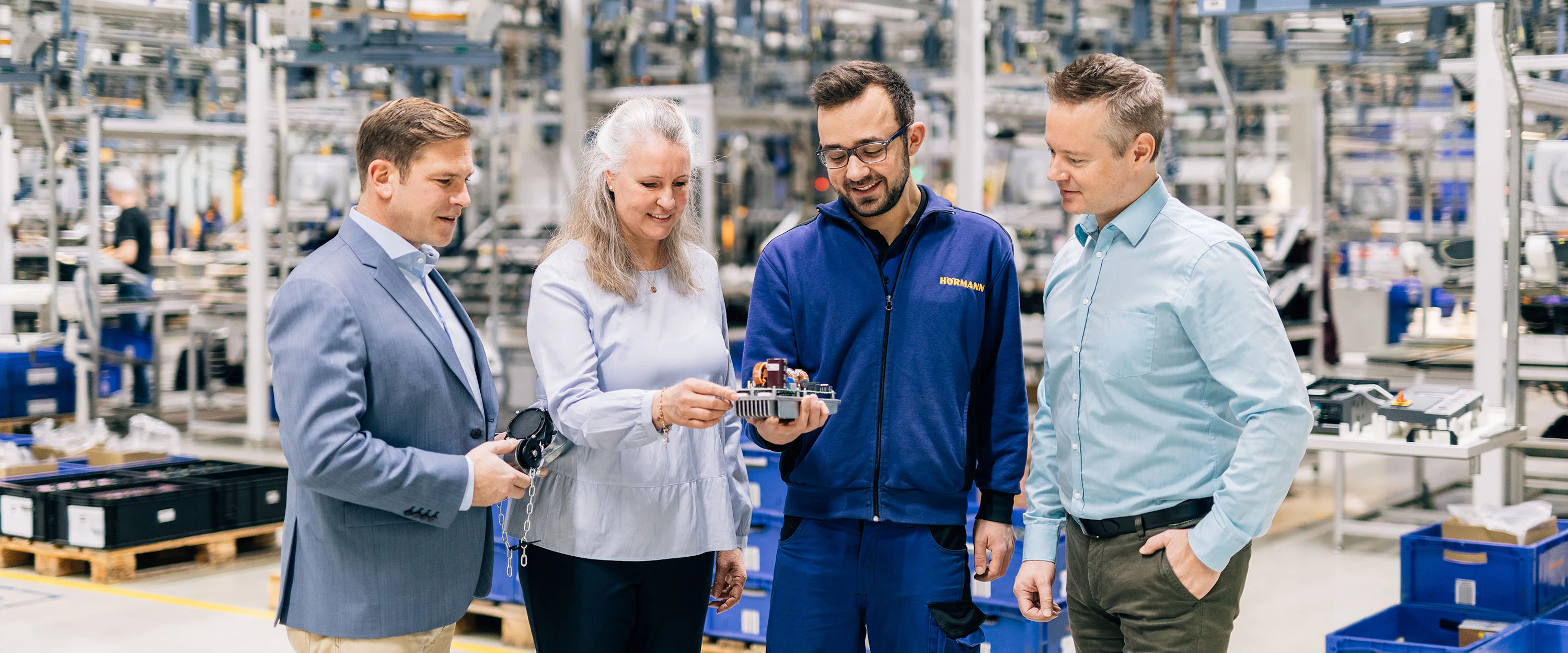 Vier medewerkers van Hörmann inspecteren een onderdeel van een van de producten