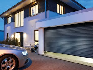 Serranda avvolgibile da garage RollMatic in Noir 2100 Sablé Anthrazit Metallic Le serrande avvolgibili RollMatic si aprono verticalmente e occupano uno spazio minimo sia all'interno che all'esterno del box auto. Grazie al loro principio costruttivo offrono massimo spazio sia...
