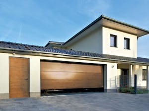 Portone sezionale da garage, grecatura L in Decograin Winchester Oak con porta pedonale laterale dall'identico aspetto Una porta pedonale laterale è sempre molto pratica se dovete prelevare in fretta qualcosa dal garage ma non volete aprire il portone. Oppure quando la vostra seconda auto è parcheggiata proprio...