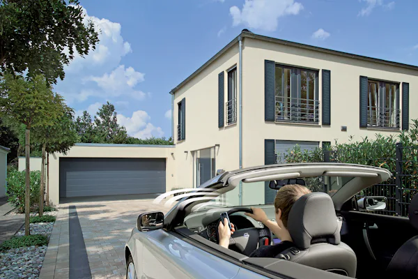 Een auto komt aanrijden bij een garage en maakt gebruik van automatische opening.