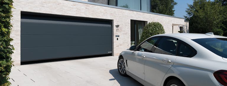 En bil har svängt upp på uppfarten och väntar på att garageporten ska öppna sig