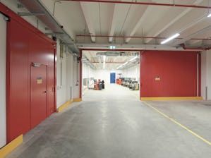 Hörmann levererar tillförlitliga drift- och riskanpassade... Röd brandskjutport i en industrifastighet.