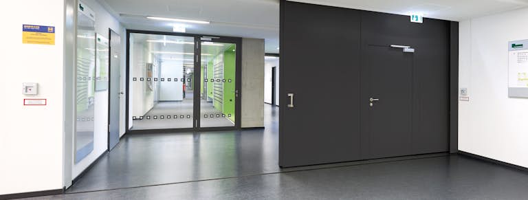 Mörk brandskjutport med gångdörr inne i en fastighet.