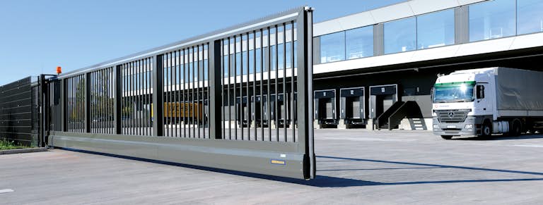 En skjutgrind öppnar sig för att släppa ut en lastbil på industriområdet.