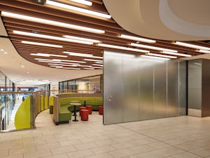 Hörmann levererar tillförlitliga drift- och riskanpassade... Silvrig brandskjurport framför område med bord, stolar och soffor.