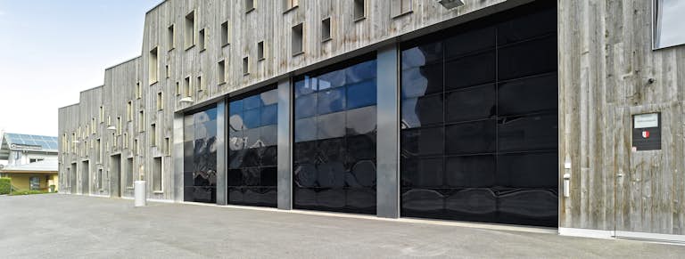 industrifastighet med träfasad och mörka helglasade portar.