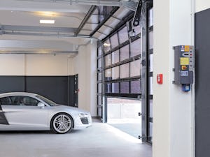 Behovet av parkeringsplatser i storstäder och tätorter ökar... Bil väntar på att åka ut från ett parkeringsgarage. Den helglasade porten öppnar sig.