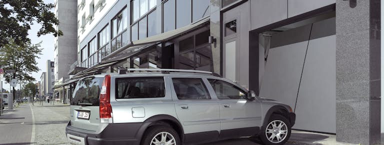 Silvrig Volvo väntar på att köra in i ett parkeringsgarage. Porten öppnas.