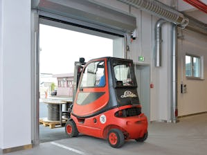 Hörmann rullportar och rullgaller i aluminium och stål är... En röd truck kör ut genom en upprullad port.