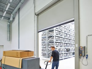 Hörmann snabbrullportar finns som inomhus- och utomhusport... En man kör en pall med en palldragare och går igenom den öppna porten.