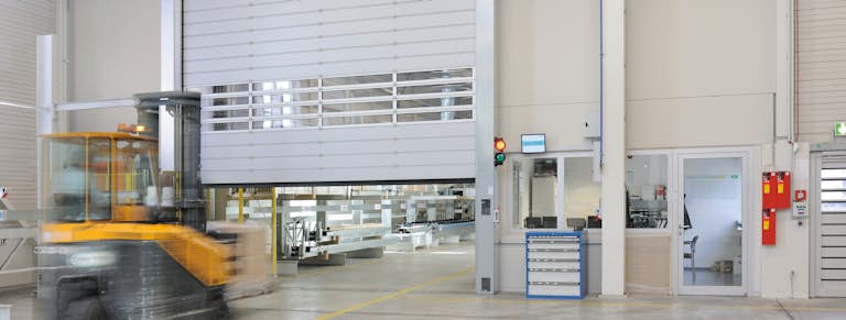 Snabbrullport öppnar sig inne i en industrifastighet så en stor gul truck kan köra igenom.