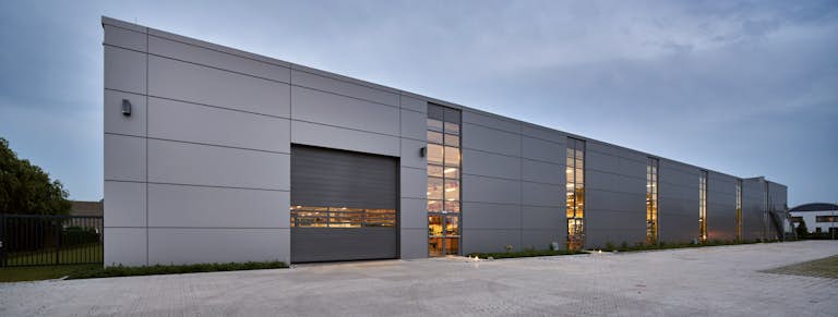Mörkgrå industriport med fönster mot en grå industrifastighet.