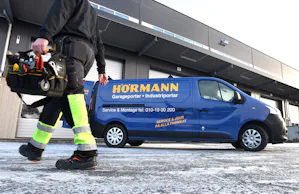 Vår felanmälan finns tillgänglig på både telefon och mejl... Servicetekniker går utanför en fastighet, intill en port står en servicebuss parkerad.